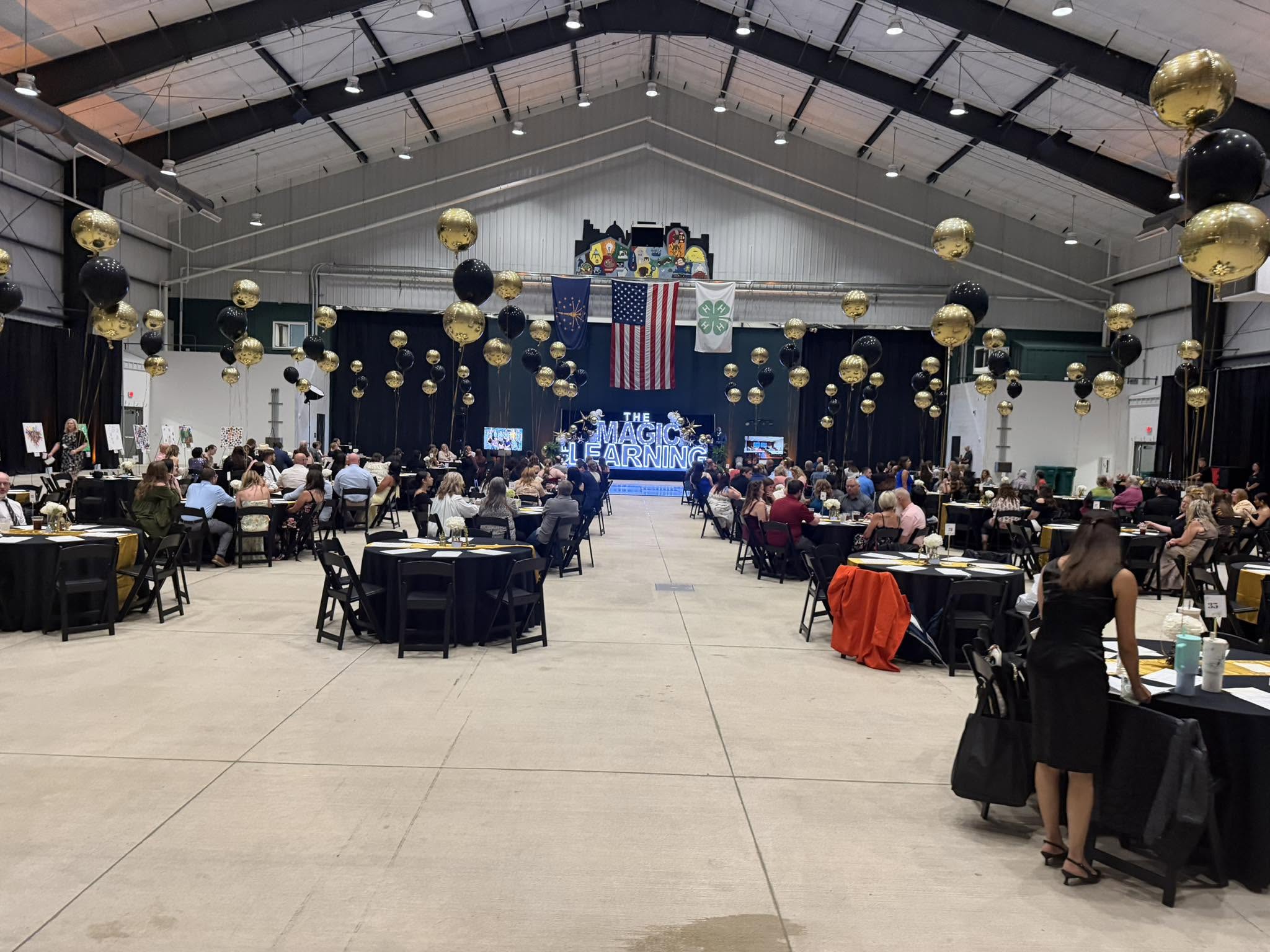 Live event — full venue with stage, projection screen, and audience