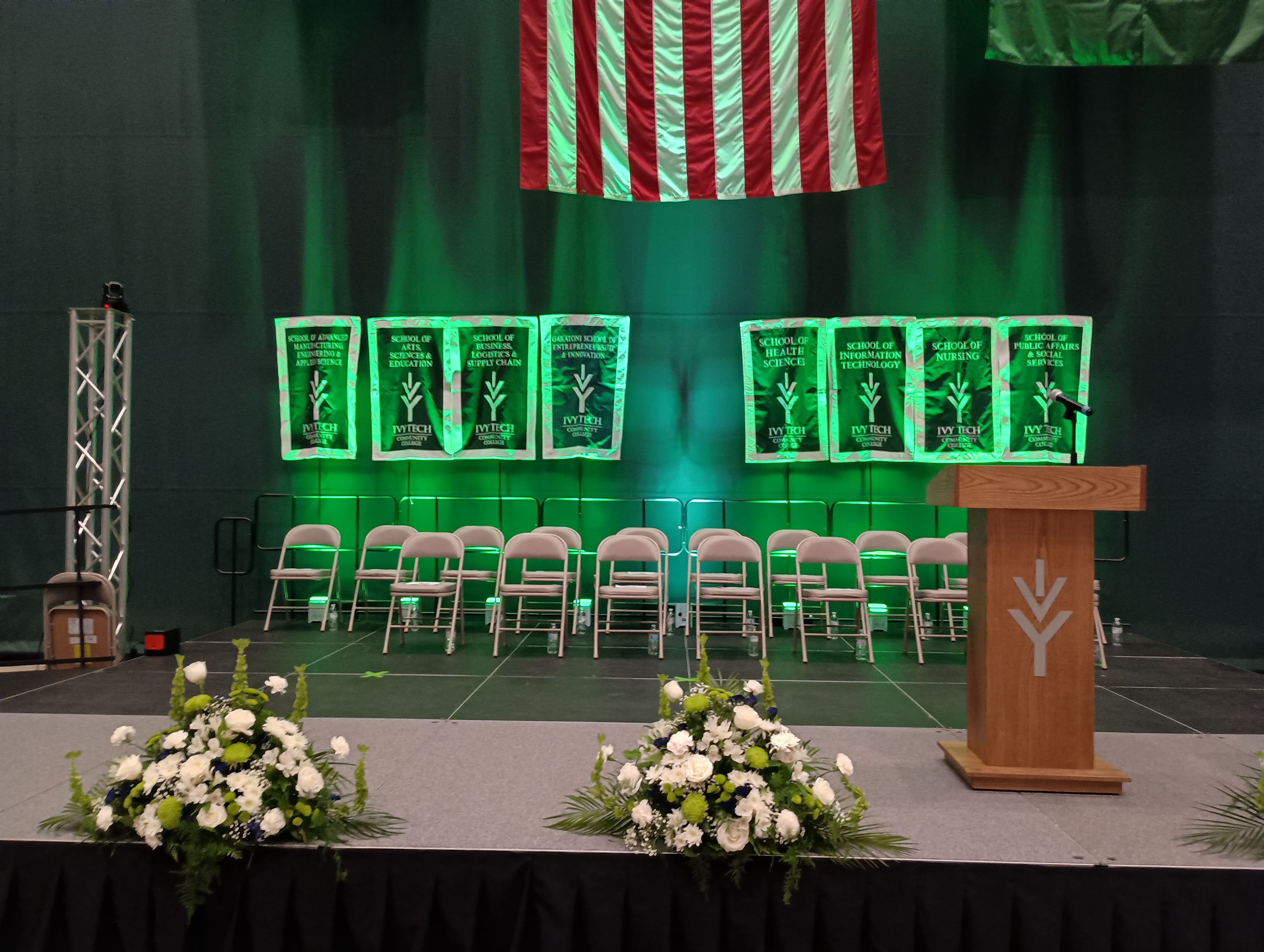 Branded event stage with podium, American flag, and floral arrangements